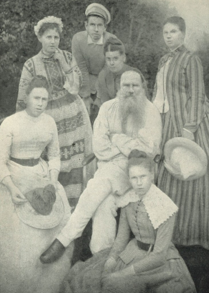 Mustavalkoinen perhepotretti jossa parrakkaan vanhan istuvan miehen ympärille on kerääntynyt kuusi ihmistä. Naisilla on yläluokkaiset kesäleningit, vanhalla miehellä työväenluokalle tyypillisempi asu.