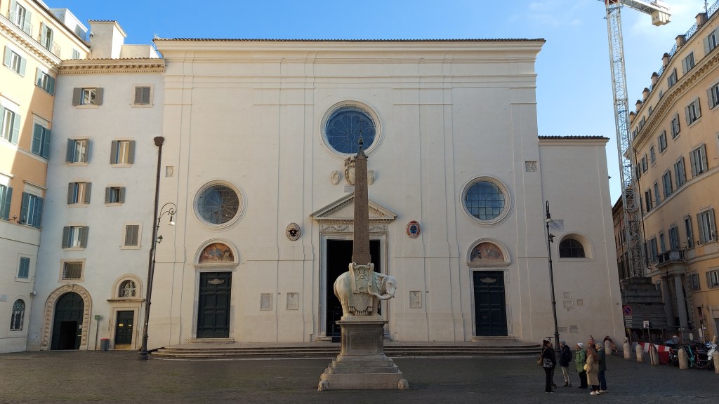 Kuva kirkon julkisivusta torilta katsottuna. torilla marmorinorsu ja obeliski.