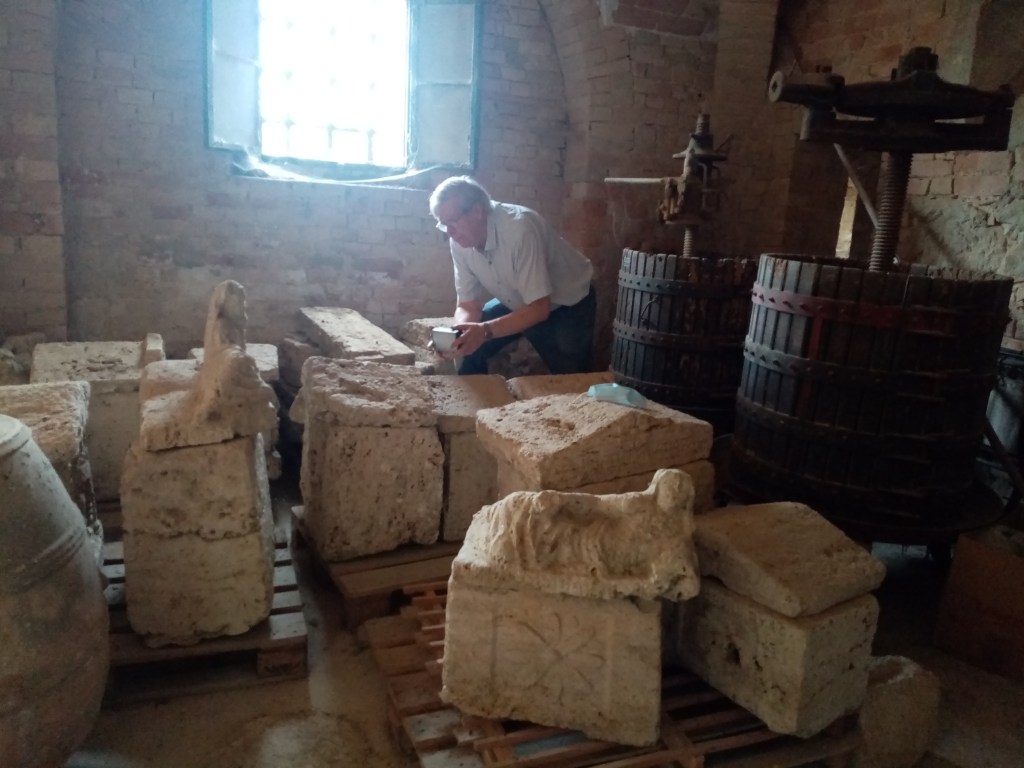 Mies nojaa eteenpäin ja tutkiskelee isoja talonmuotoisia cippus-kiviä. 