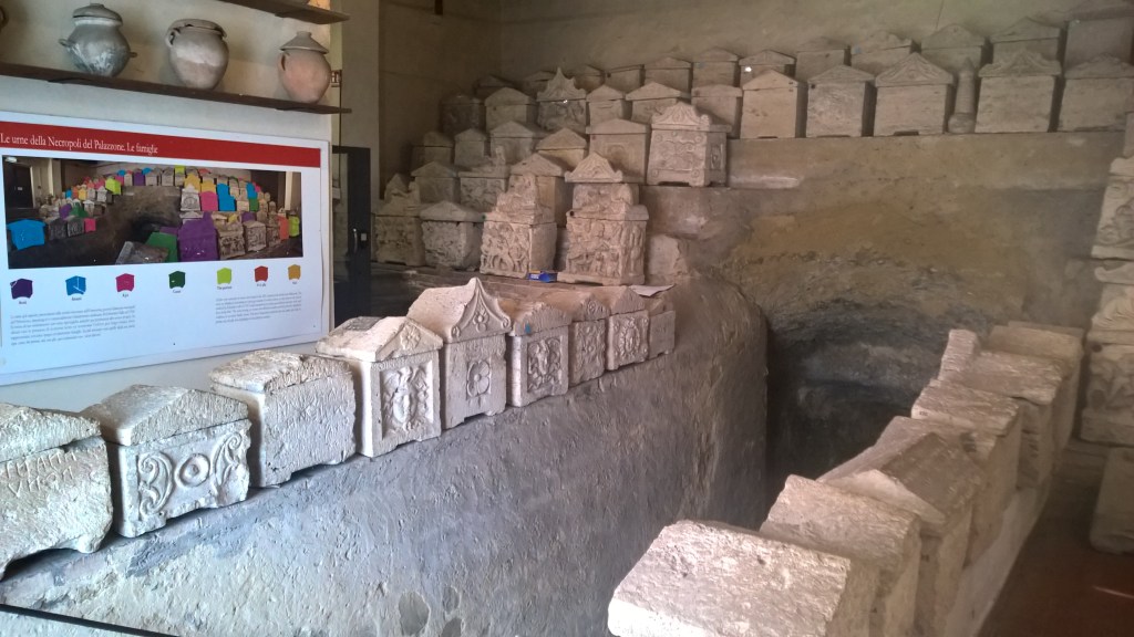 Huone täynnä talonmuotoisia cippus-kiviä asetettu riveihin. 